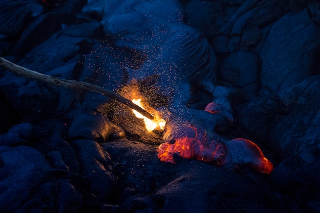 a stick catching on fire poking cooling lava